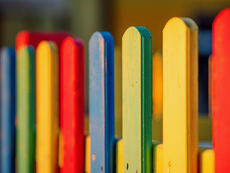 The colorful painted wooden boards on the fence around a playground are illuminated by the rays of the setting sun. Pula, Croatia - January 3, 2025の写真素材