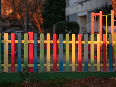 The colorful painted wooden boards on the fence around a playground are illuminated by the rays of the setting sun. Pula, Croatia - January 3, 2025の写真素材