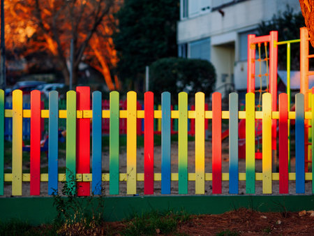 The colorful painted wooden boards on the fence around a playground are illuminated by the rays of the setting sun. Pula, Croatia - January 3, 2025の写真素材