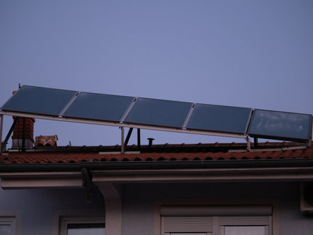 Solar panels installed above the tiled roof. Ventilation pipe with rotating nozzle. Solar energy concept. Pula, Croatia - January 3, 2025の写真素材
