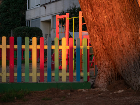 Pine tree illuminated at sunset. Tree trunk. Multicolored painted wooden boards on the fence around the playground are illuminated by the rays of the setting sun. Pula, Croatia - January 3, 2025の写真素材