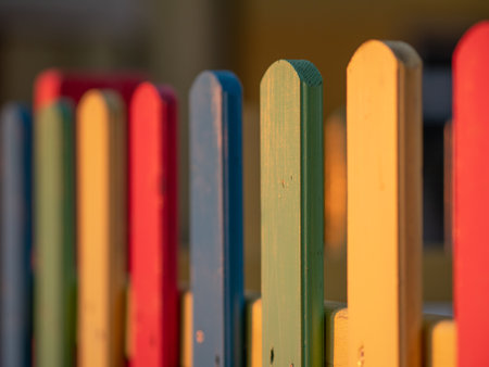 The colorful painted wooden boards on the fence around a playground are illuminated by the rays of the setting sun. Pula, Croatia - January 3, 2025の写真素材