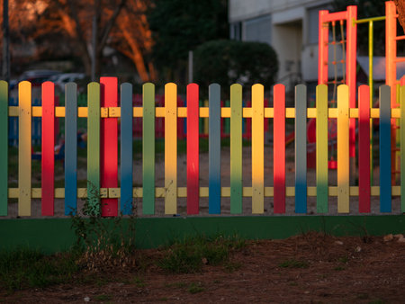 The colorful painted wooden boards on the fence around a playground are illuminated by the rays of the setting sun. Pula, Croatia - January 3, 2025の写真素材