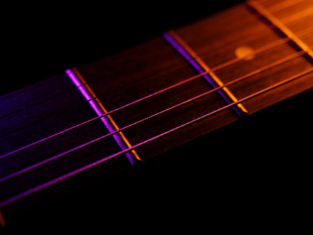 Electric guitar strings close up. Musical instrument details. Concert color contrast lighting. Six-string guitar during performance. Bright colors on dark bsckground. Cinematic light. Copy spaceの写真素材