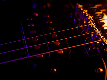 Electric guitar strings close up. Musical instrument details. Concert color contrast lighting. Six-string guitar during performance. Bright colors on dark bsckground. Cinematic light. Copy spaceの写真素材