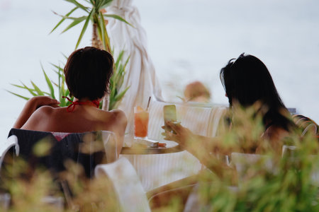 Several women relax at cafe tables. Beach bar. Summer evening. Fazana, Croatia - circa 2025の写真素材