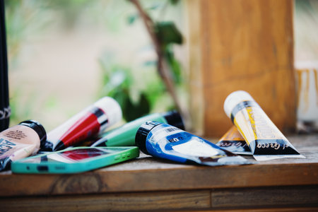 Tubes of acrylic paints lie on a wooden board next to a mobile phone. Artist's studio. Fazana, Croatia - circa 2025の写真素材
