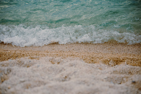 Gentle waves roll onto a beach of small pebbles. Surf on the beach. Background for a tourist brochure.の写真素材