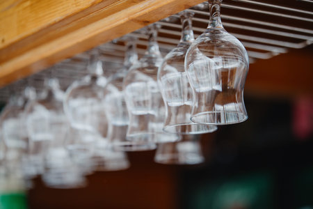 Glasses hanging upside down above the bar counter. Clean transparent glasses for alcoholic drinks...
