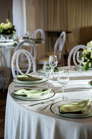 Elegant wedding banquet hall features a beautifully set table with floral centerpiece, glassware, and soft lighting creating a romantic atmosphereの写真素材