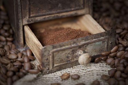 Antique coffee grinder filled with coffee beans - selective focus on ground coffeeの写真素材