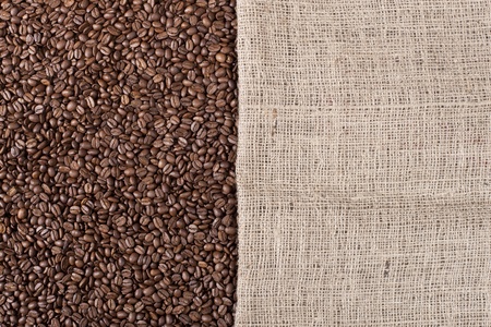Background image of many coffee beans and a canvas sack filling the pictureの写真素材