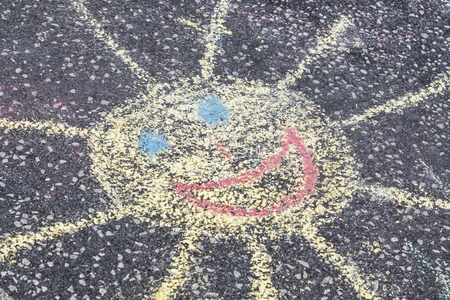 kids chalk drawing of a sun on asphaltの写真素材