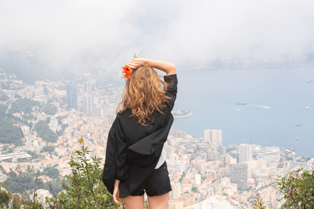 Young Woman In Black. Beautiful Aerial View of Monaco in The Backgroundの写真素材