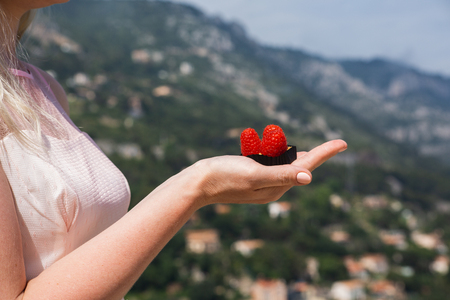 Cupcakes with raspberries in woman's hand in nature backgroundの写真素材