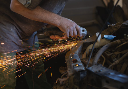 The Employee of The Car Service Station Produces Body Repair with a Welding Machine in Hand. Sparks...