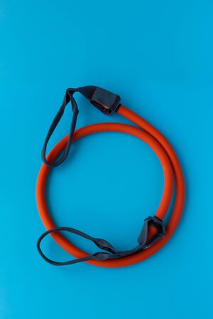 Orange Elastic Rubber Band on a Blue Background. Fit, fitness, exercise, workout and healthy lifestyle. Copy space for textの写真素材
