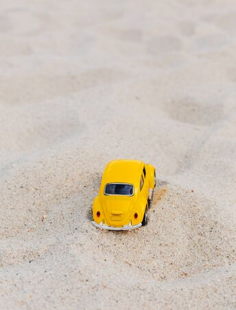 Miami, FL, USA - July 13, 2019: Yellow Small Toy Car on sand nature background.  Summer vacation concept. Copy Spaceのeditorial素材