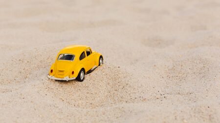 Miami, FL, USA - July 13, 2019: Yellow Small Toy Car on nature background. Retro car on Beach and Sand background. Summer vacation conceptのeditorial素材
