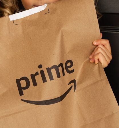 Miami, FL, USA - August 6, 2019:  Amazon Prime package in a hands in at apartment door. Amazon is an online company and is the largest retailer in the world.Amazon Prime is a service from Amazon which delivers parcels fast, in 1 dayのeditorial素材