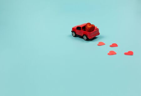 Valentines Day Concept. Miniature red toy car with red heartsの写真素材
