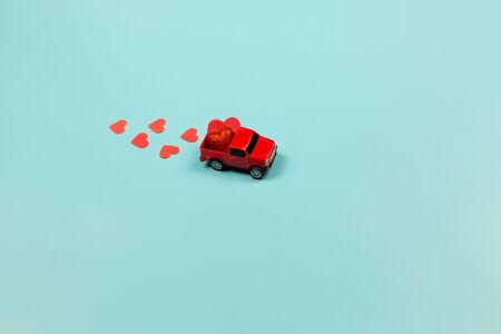 Valentines Day Concept. Miniature red toy car with red heartsの写真素材
