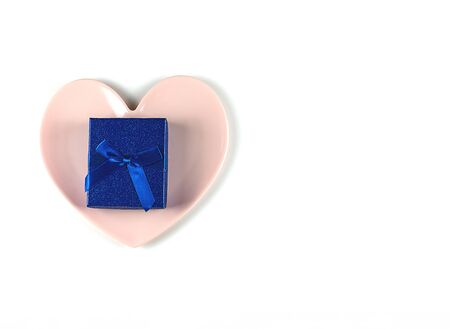 Gift box with a bow, a pink plate in the shape of a heart on white background.Concept of Valentines Day or wedding romantic themeの写真素材