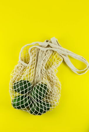 Healthy fresh Hass avocado in zero waste net bag on yellow background. Plastic free concept. Copy Spaceの写真素材