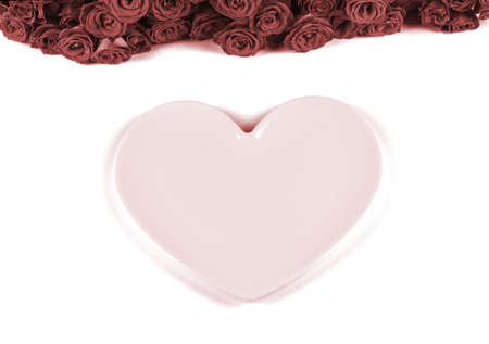 Table setting for Valentines Day with beautiful red roses and pink plate in the shape of a heart on white background.Valentines day dinner concept.の写真素材