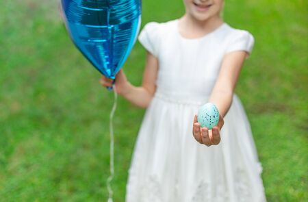 Adorable Girl Holding blue Easter egg and blue Balloon.の写真素材