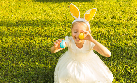 Adorable little girl wearing bunny ears holding Easter eggs.