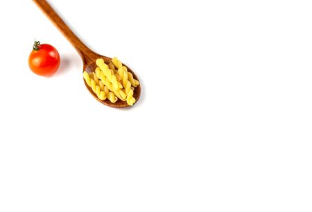 Raw dry Italian pasta in wooden spoon with tomato on white background. Food and drink concept. Top view. Copy Spaceの写真素材