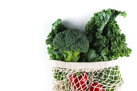 Eco friendly mesh bag with organic vegetables: Kale salad, broccoli, avocado, bell peppers on white background. Flat lay, top view. Zero waste concept. Healthy clean eating diet and detox. Copy spaceの写真素材