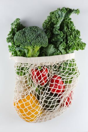 Eco friendly mesh bag with organic vegetables: Kale salad, broccoli, avocado, bell peppers on a white background. Zero waste concept. Healthy clean eating diet and detox. Top viewの写真素材