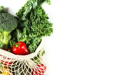 Eco friendly mesh bag with organic vegetables: Kale salad, broccoli, avocado, bell peppers on white background. Flat lay. Zero waste concept. Healthy clean eating diet and detox. Copy space. Close upの写真素材