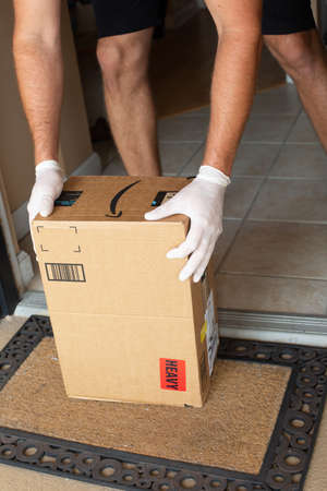 Miami, FL, USA - March 25, 2020: Amazon Prime package in a hands in at apartment door. Quarantine due Coronavirus. Amazon is an online company and is the largest retailer in the world.のeditorial素材