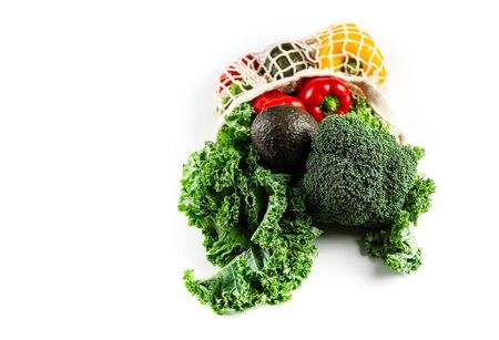 Eco friendly mesh bag with organic vegetables: Kale salad, broccoli, avocado, bell peppers on a white background. Zero waste concept. Healthy clean eating diet and detox. Top view, Copy spaceの写真素材