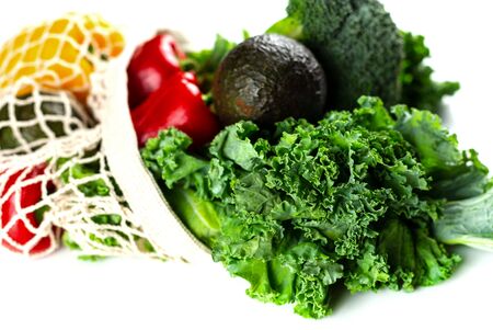 Eco friendly mesh bag with organic vegetables: Kale salad, broccoli, avocado, bell peppers on a white background. Zero waste concept. Healthy clean eating diet and detox. Top view, Copy spaceの写真素材