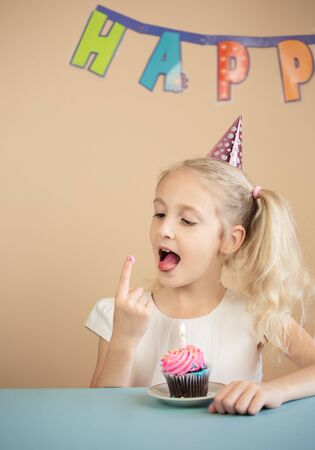 Portrait Caucasian Girl wearing birthday hatÂ  with birthday cake. Happy Birthday Concept.の写真素材