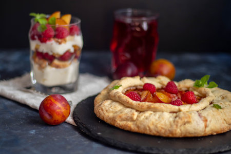 Biscuit with plums. Bake in the oven Near gray fabric and metal devices.
