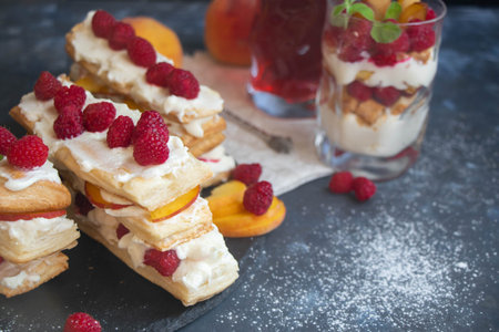 Dessert Milfey. Raspberry berries and peach slices. In the background, the same, only in a glass. On...