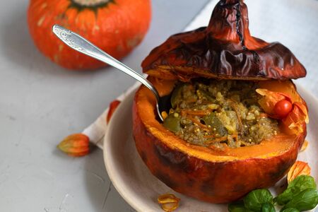 Baked pumpkin stuffed with vegetable stew with rice. Nearby are the berries of physalis, and in the background is a fresh orange tavern. healthy lifestyle. Proper nutrition. Diet.の写真素材