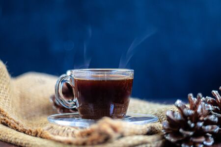 Coffee in a transparent cup. Hot, invigorating drink. Near cones in sparkles, coffee beans are scattered.の写真素材