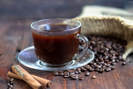 Coffee in a transparent cup. Hot, invigorating drink. Near cones in sparkles, coffee beans are scattered.の写真素材