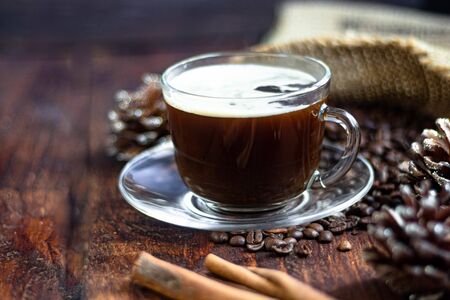 Coffee in a transparent cup. Hot, invigorating drink. Near cones in sparkles, coffee beans are scattered.の写真素材
