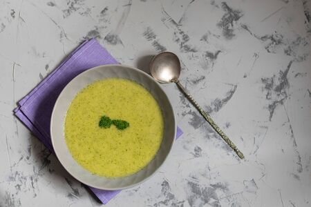 Detox green broccoli cream soup with chia seeds, red onions, green peppers, cherry tomatoes and croutons on a gray background. Healthy eating concept. Copy space.の写真素材