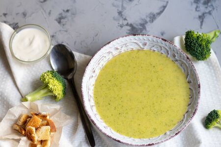 Detox green broccoli cream soup with chia seeds, red onions, green peppers, cherry tomatoes and croutons on a gray background. Healthy eating concept. Copy space.の写真素材