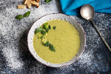Detox green broccoli cream soup with chia seeds, red onions, green peppers, cherry tomatoes and croutons on a gray background. Healthy eating concept. Copy space.の写真素材