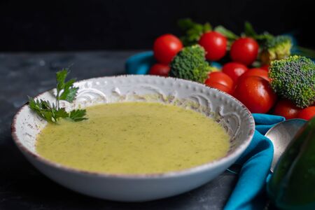 Detox green broccoli cream soup with chia seeds, red onions, green peppers, cherry tomatoes and croutons on a gray background. Healthy eating concept. Copy space.の写真素材