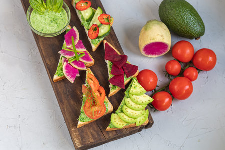 Holiday sandwiches of various shapes. Vegetarian and more. Dressing with avocado and spinach and creamy yogurt. Top cucumber, turnips, tomatoes, salami, balyk, red caviar, spinach, eggs and olives.の写真素材